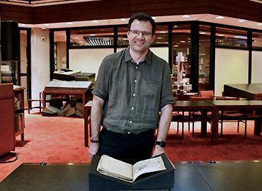 Sebastian Sobecki stands over Sir John Mandeville’s Travels, written in the mid-1300s. Photo credit: All photos Diana Tyszko.